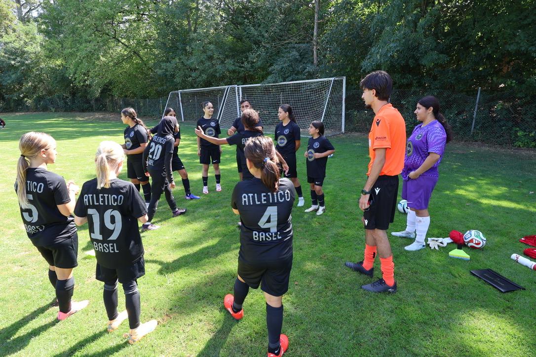 Trainer mit jungen Fussballerinnen in schwarzen Trikots